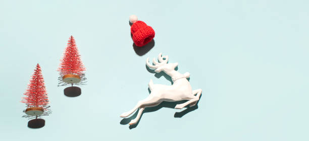 Little fawn with red Santa Claus hat looking into a camera on a cold winter eveningt.