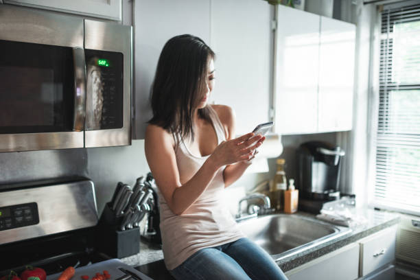 istock chinese woman text messaging in the kitchen 2185924182