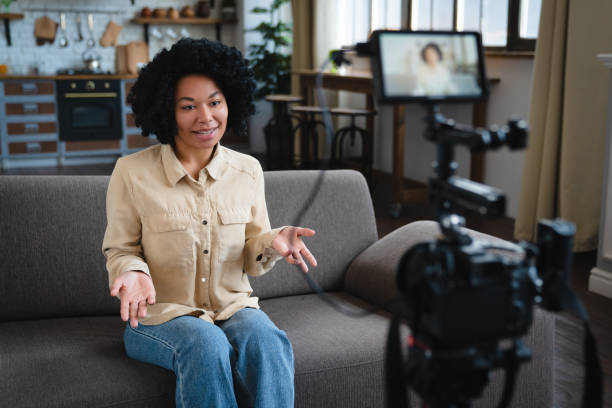 istock Smiling friendly african woman internet teacher tutor looking at camera talking, black mixed race millennial female vlogger speaking making video vlog, job interview at home, portrait 2185928206