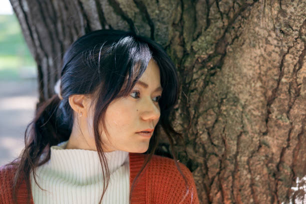 istock Woman leaning on tree and looking at view in public park 2185929525