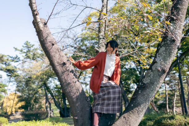 istock Woman climbing on tree in public park 2185929569