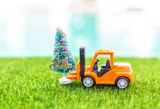 Forklift truck with Christmas tree on green grass over blurred background, Christmas background idea