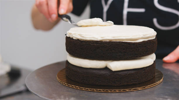 istock Close Up Of Baker Spreading Buttercream On Chocolate Cake 2185943936