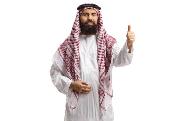Saudi arab man wearing a traditional thobe and gesturing a thumb up sign isolated on white background