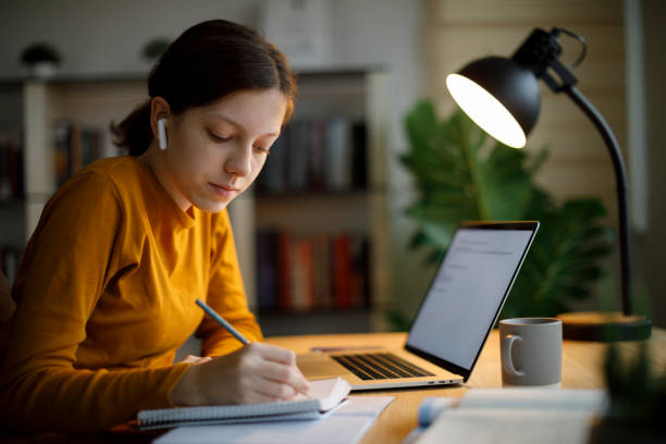 istock Teenage girl taking notes while watching an online tutorial on her laptop at home 2185949178