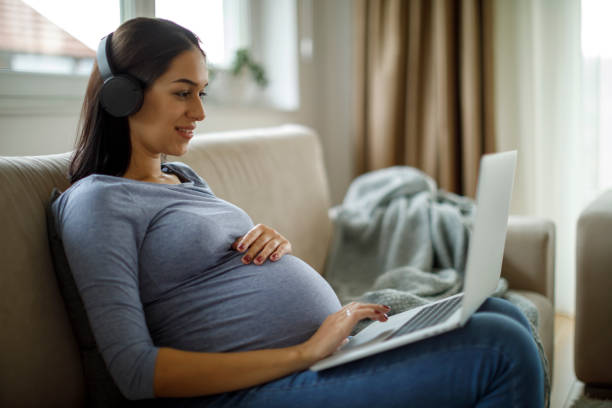 istock Pregnant woman watching a tutorial on her laptop at home 2185949286