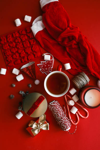 istock Festive Christmas composition with holiday decorations, red cup of tea, candy canes, marshmallows, and gifts on a vibrant red background 2185949997