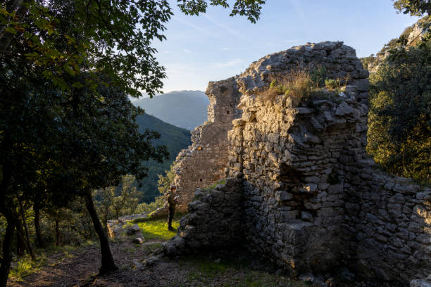 Young man flies drone in old fortress ruin above hills, Liguria
