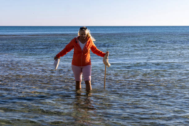 Mature woman explores shallows near beach in autumn, Liguria