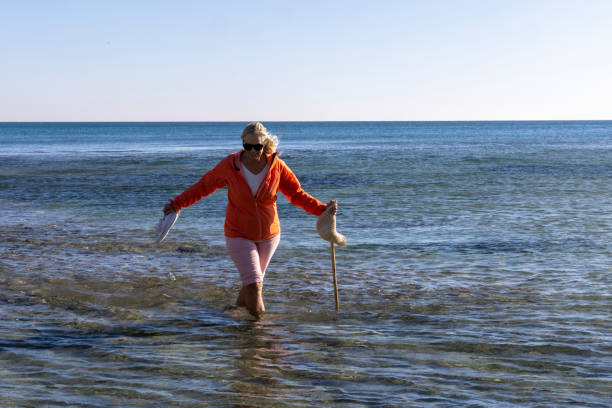 Mature woman explores shallows near beach in autumn, Liguria