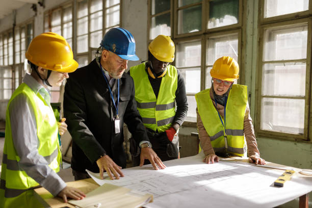 istock Team of Architects Examining Blueprints 2185951467