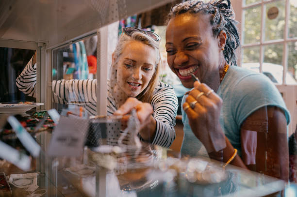 Mature women looking at a jewellery cabinet in a small vintage clothing store.