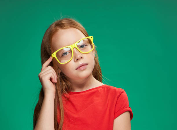 istock red-haired girl emotions yellow glasses studio green background 2185952592