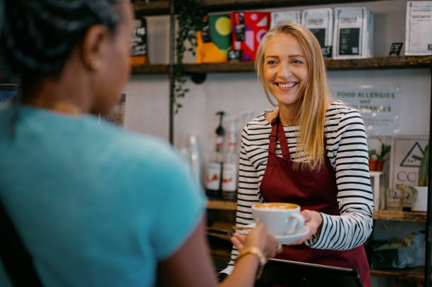 istock A smiling barista serves a coffee to a customer in a cafe. 2185953258