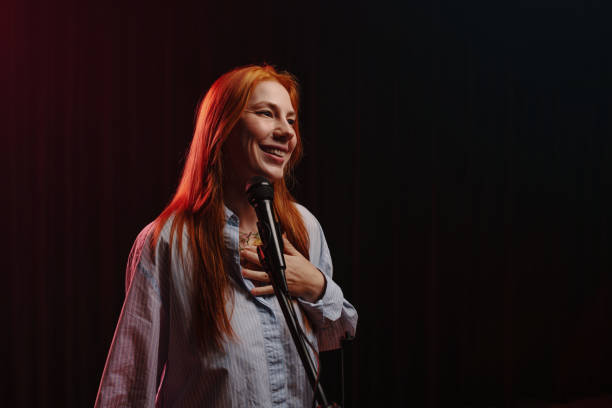 istock Smiling Woman Holding Microphone Against Dark Background 2185953552