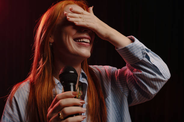 Laughing Woman Holding Microphone and Covering Face