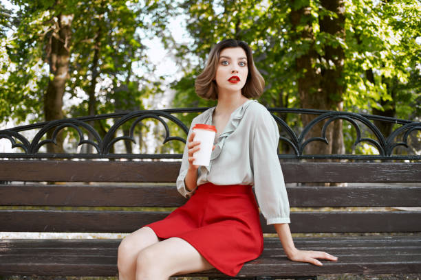 istock cute blonde sitting on a park bench coffee summer leisure 2185953563