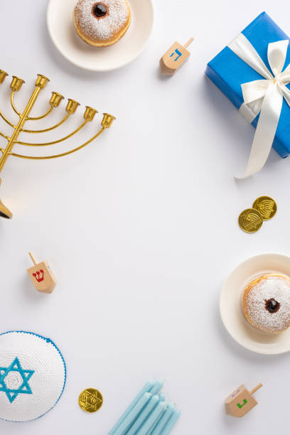 istock Festive Hanukkah vertical arrangement featuring a menorah, dreidels, and donuts with blue candles and a gift box, symbolizing the joyous holiday of lights 2185957188
