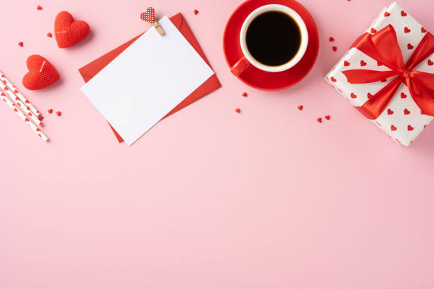 istock A romantic Valentine's Day themed arrangement featuring a wrapped gift, a cup of coffee, a blank card, and heart decorations on a pink background 2185957244