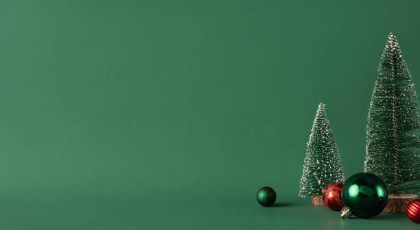 istock A minimalist setup featuring small Christmas trees and colorful baubles against a green backdrop, evoking holiday spirit 2185957283