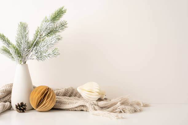 istock Minimalist side view Scandinavian Christmas decor featuring frosted pine branches in a vase, cozy knit blanket and geometric ornaments conveying a sense of warmth and winter elegance 2185957286