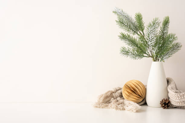 istock A side view simple Scandinavian style setup featuring a white vase with frosted pine branches, a paper ornament, and cozy knitted scarf. Perfect for winter holiday inspiration and minimalist decor 2185957305