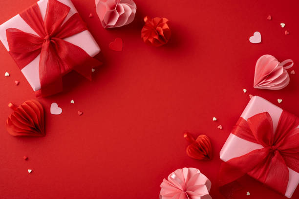 istock Valentine's Day themed image featuring elegantly wrapped gifts with red ribbons surrounded by heart decorations on a vibrant red background, evoking romance and love. 2185957325