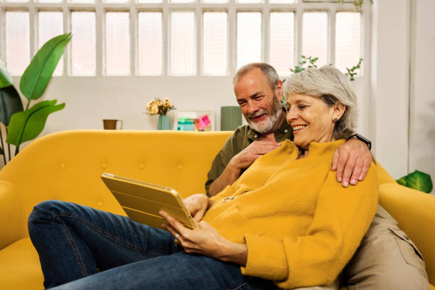 istock Happy senior couple relaxing on sofa using digital tablet at home 2185969791