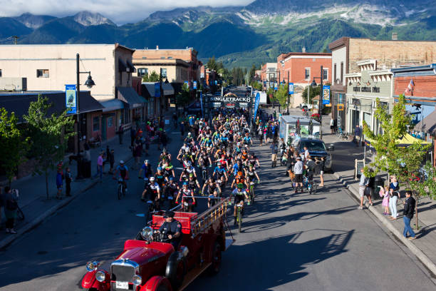 The start of the TransRockies Singletrack 6 mountain bike race on Main Street Fernie, British Columbia, Canada. The Singletrack 6 is a six-day mountain bike race in British Columbia, Canada, that is held in different host towns for each stage. The vintage Fernie fire engine leads the race down Main Street in the morning. (John Gibson Photo / GibsonPictures)