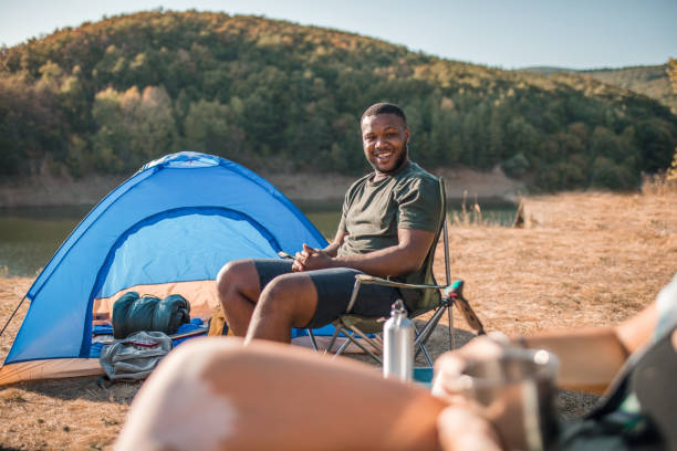 istock Smiling black man camping by lake with friends 2185970330