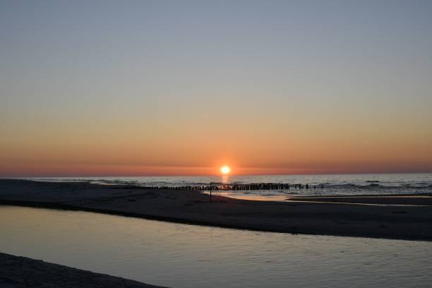 istock Sunset over calm sea with beach silhouette. 2185971721