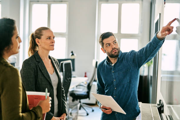 istock Male professional explaining new project over whiteboard to team in office 2185972214