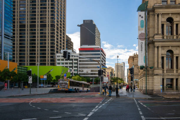 A bustling street intersection in downtown Brisbane, featuring modern buildings, historic architecture, and pedestrians enjoying the urban scenery.