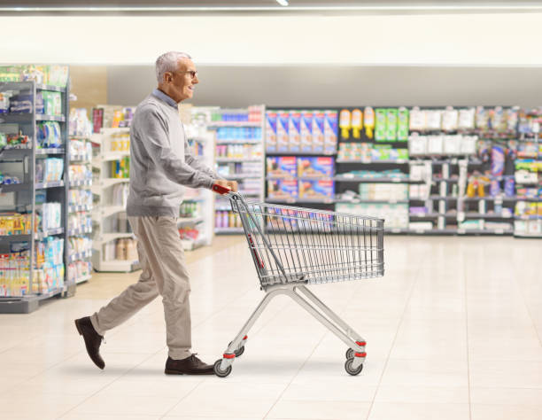 istock Elderly man pushing an empty shopping cart inside a supermarket 2185977677