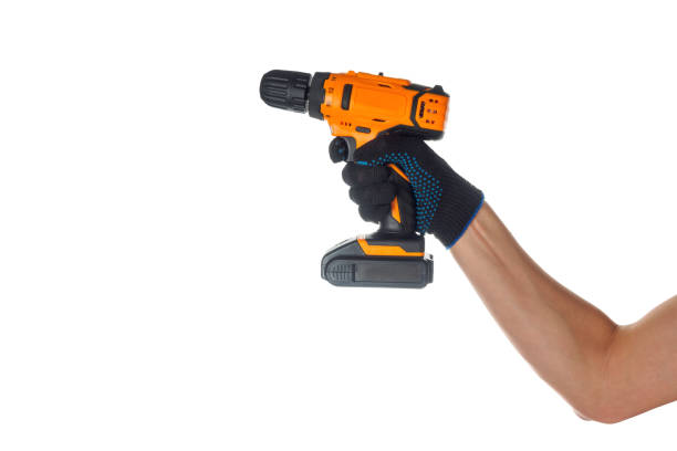 istock Cordless screwdriver in the hand of a construction worker on a white background. The robust body of the tool and the confident grip of the working hand are visible, emphasizing professionalism and readiness to perform construction 2185978496