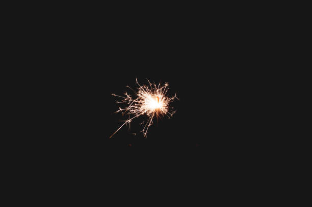 Sparklers sparkle brightly against a black background, creating the effect of magic and celebration, filling the atmosphere with joy.