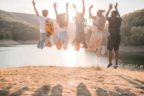 istock Back view of a multiracial group of friends jumping for joy while spending the day camping by the lake 2185982048