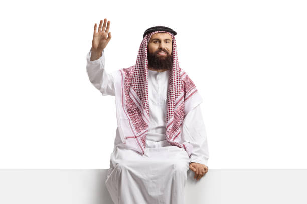 istock Saudi arab man sitting on a blank panel and waving 2185982636