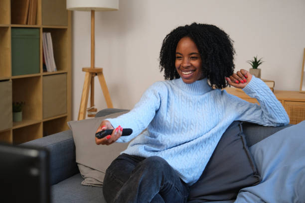istock Young woman relaxing on sofa watching television and smiling 2185982930