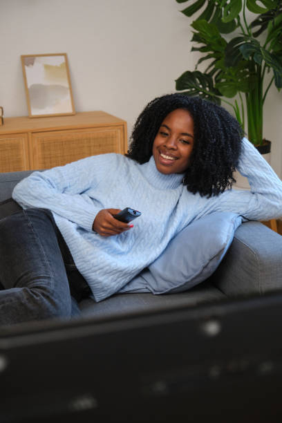 istock Young woman relaxing on sofa watching television at home 2185983069