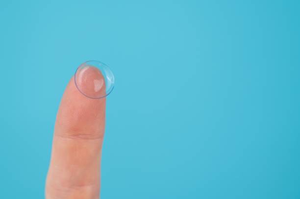 istock Woman holding contact lens on blue background. 2185983621