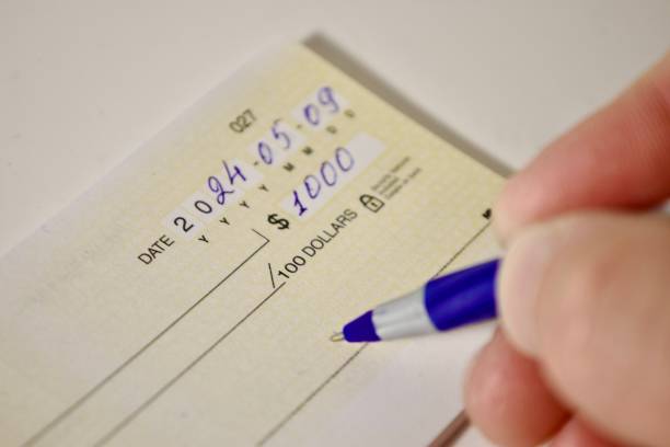 istock hand with pen filling out bank check 2185983940