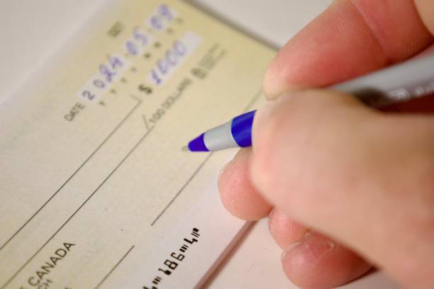 istock hand with pen filling out bank check 2185983943