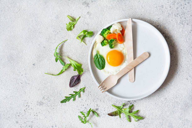 istock Healthy breakfast of fried egg and boiled vegetables with spinach on a light background. Healthy food concept, minimalism, top view. 2185984590