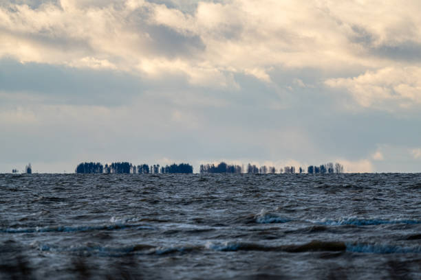 Silhouetted islands visible across a wavy sea under a cloudy sky, creating a serene and remote coastal scene.