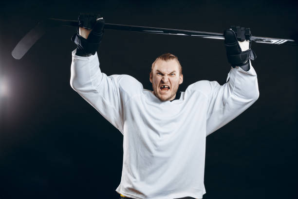 Portrait of cheerful handsome hockey player getting into the mood for winning before game starts. Sportsman in white uniform celebrating the victory. Sport, Achievements and People concept