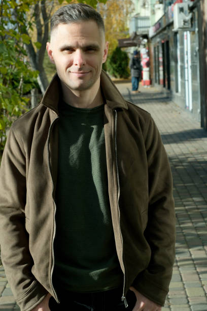 istock Man enjoying a sunny stroll on a quaint street lined with shops and trees 2185992060
