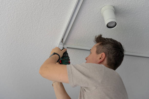 istock A person is attaching a light fixture to the ceiling using a drill. 2185993360