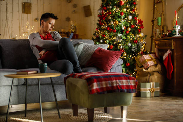 istock Thoughtful woman sitting on sofa at Christmas looking away 2185993698