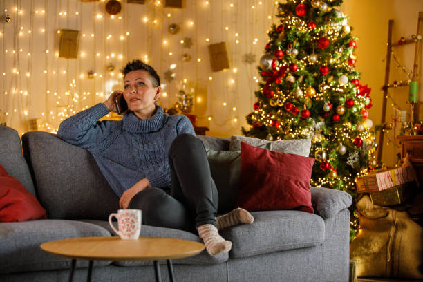 istock Woman sitting on sofa at home, talking on her mobile phone 2185993702